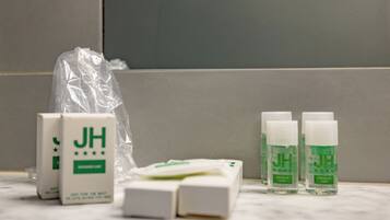 A bathroom with a white marble countertop, a white sink, and a mirror. There are four bottles of 'Intimate Care' and two boxes of 'Brewer's Cup' on the counter.