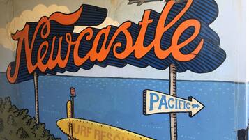 A mural with the word 'Newcastle' and a surf rescue boat.