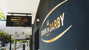 A building facade with the signage "Crown on Darby" and a contact number. - Crown on Darby (Cooks Hill)