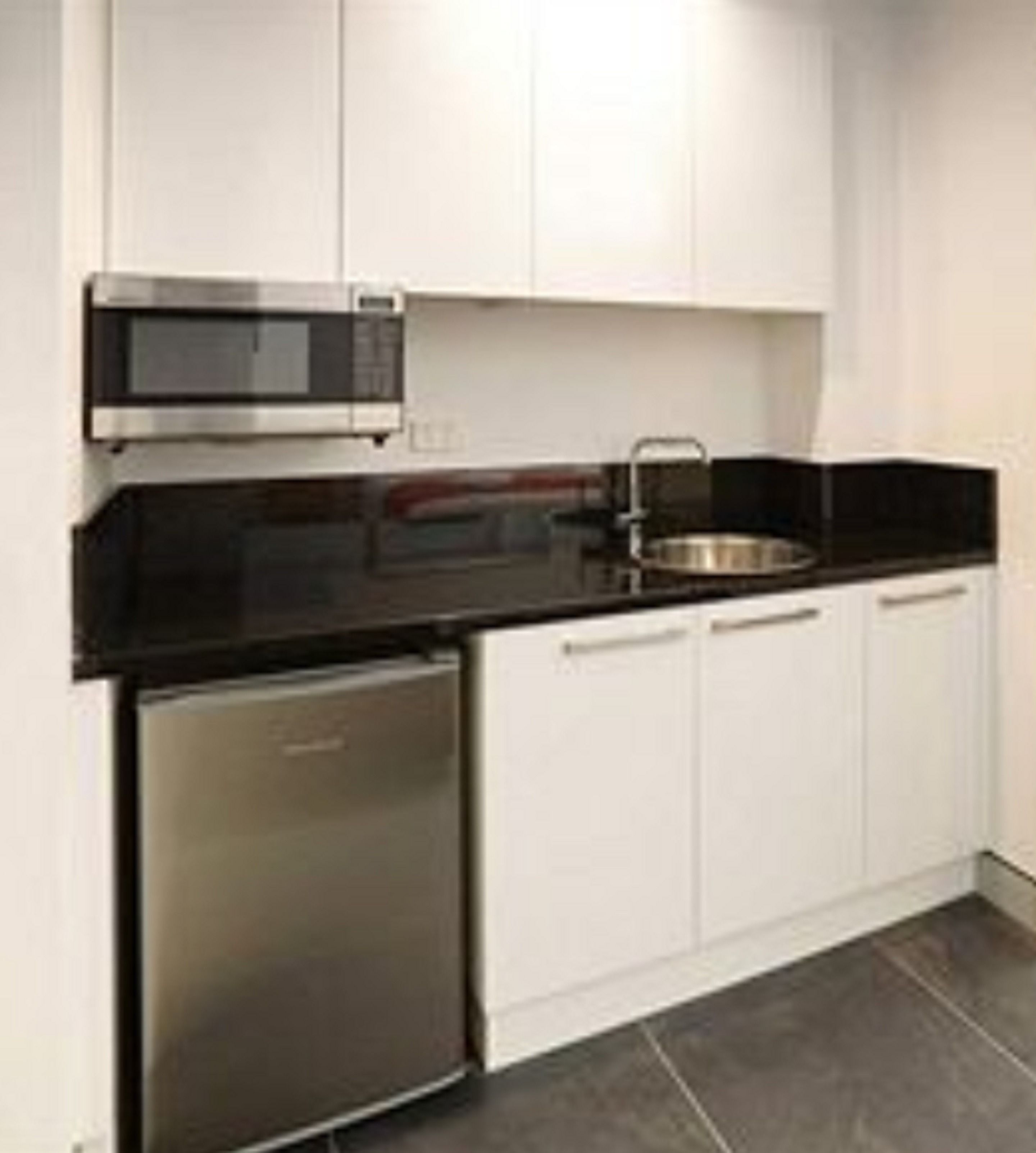 A modern kitchen with stainless steel appliances, white cabinets, and a black countertop.