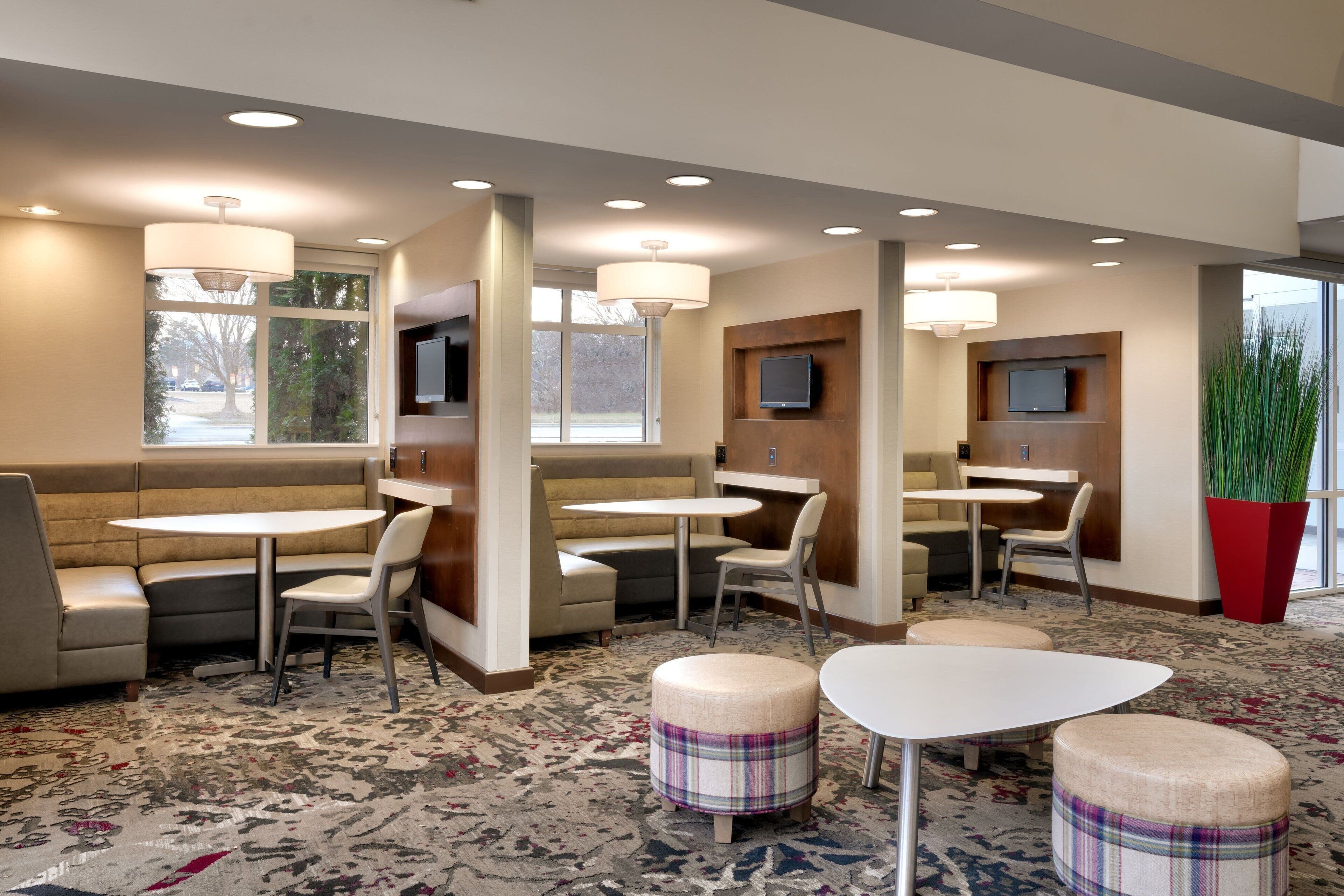 A modern hotel lobby with seating areas, tables, and a large window.
