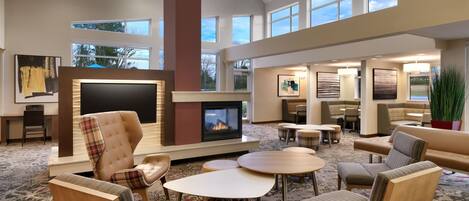 A spacious lounge area with a fireplace, comfortable seating, and large windows offering views of the outdoors.