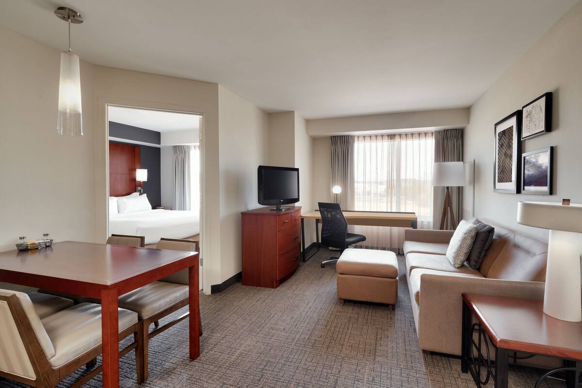 Una habitación de hotel con cama, escritorio, televisor, sofá y mesa de comedor.