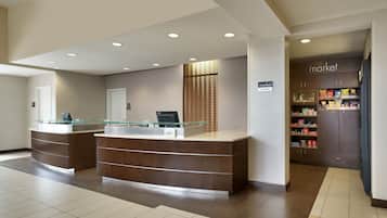 A reception area with a glass-top desk, a digital screen, and a wall-mounted sign.