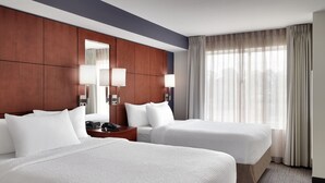 A hotel room with two beds, a wooden headboard, a nightstand with a lamp, and a large window with curtains. - Residence Inn by Marriott Greenville (Greenville)