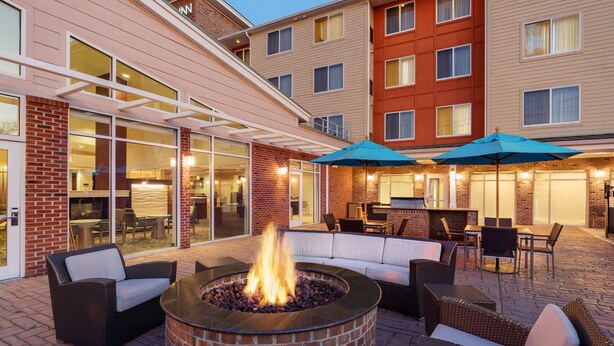 An outdoor patio area with a fire pit, seating, and umbrellas. - Residence Inn by Marriott Greenville (Greenville)