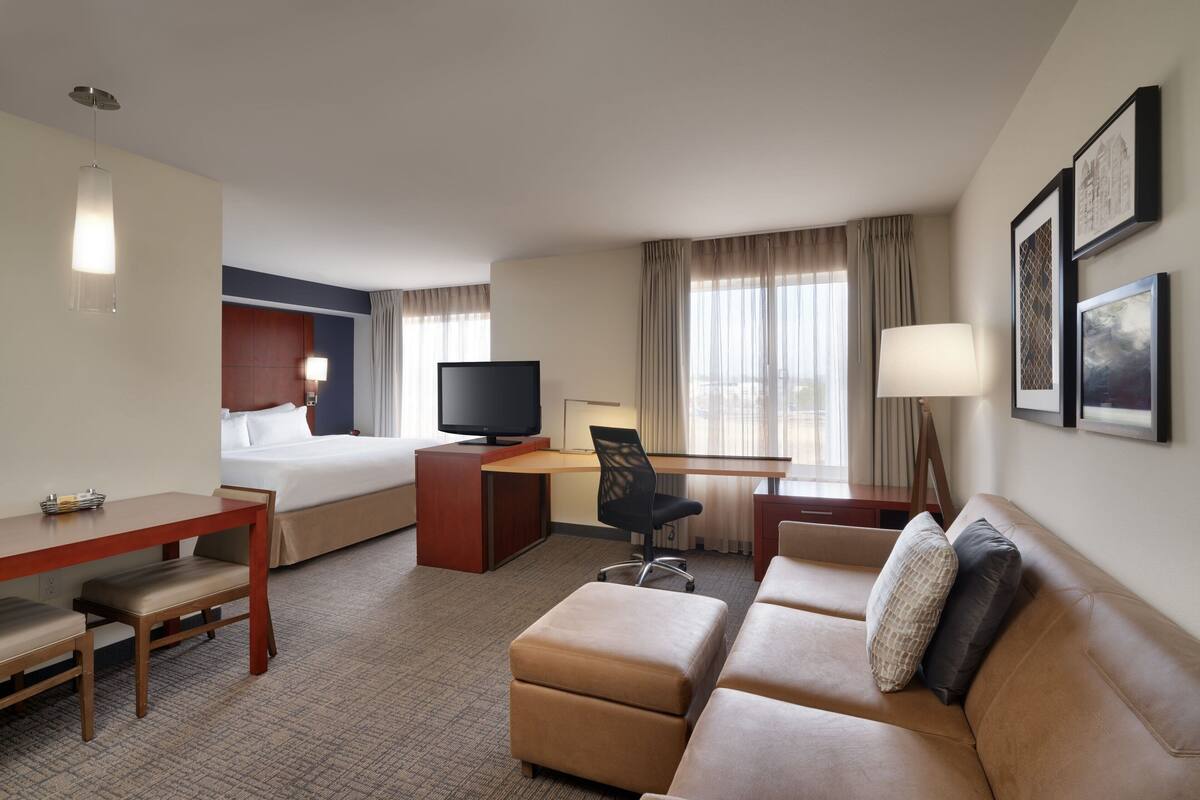 Habitación de hotel con cama, escritorio, televisión y sofá.
