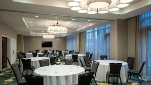 A conference room with round tables, chairs, and a large window with curtains. - Residence Inn Arlington Ballston (Arlington)