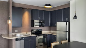 A modern kitchen with dark cabinets, stainless steel appliances, a built-in oven, microwave, and refrigerator. - Residence Inn Arlington Ballston (Arlington)