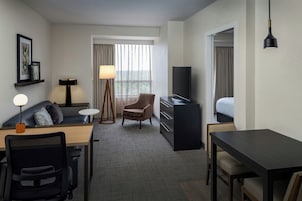 Habitación de hotel con escritorio, silla, sofá, televisión y cama.