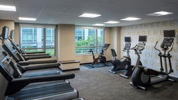Une salle de sport équipée de plusieurs tapis de course, de vélos d’appartement et d’un mur orné de messages motivants.