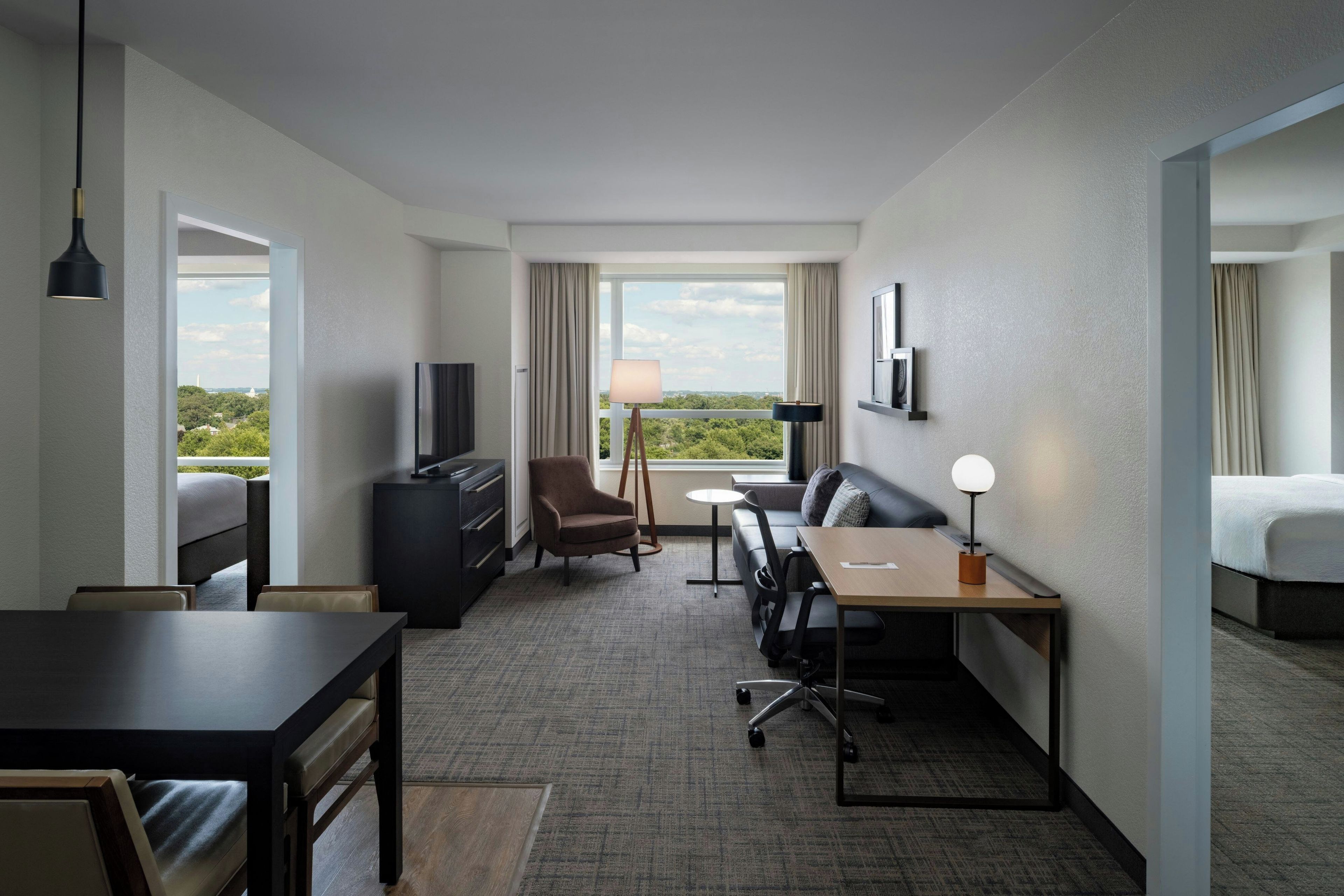 Ein Hotelzimmer mit Bett, Schreibtisch, Stuhl, Fernseher und Blick ins Freie.