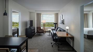 Ein Hotelzimmer mit Bett, Schreibtisch, Stuhl, Fernseher und Blick ins Freie.
