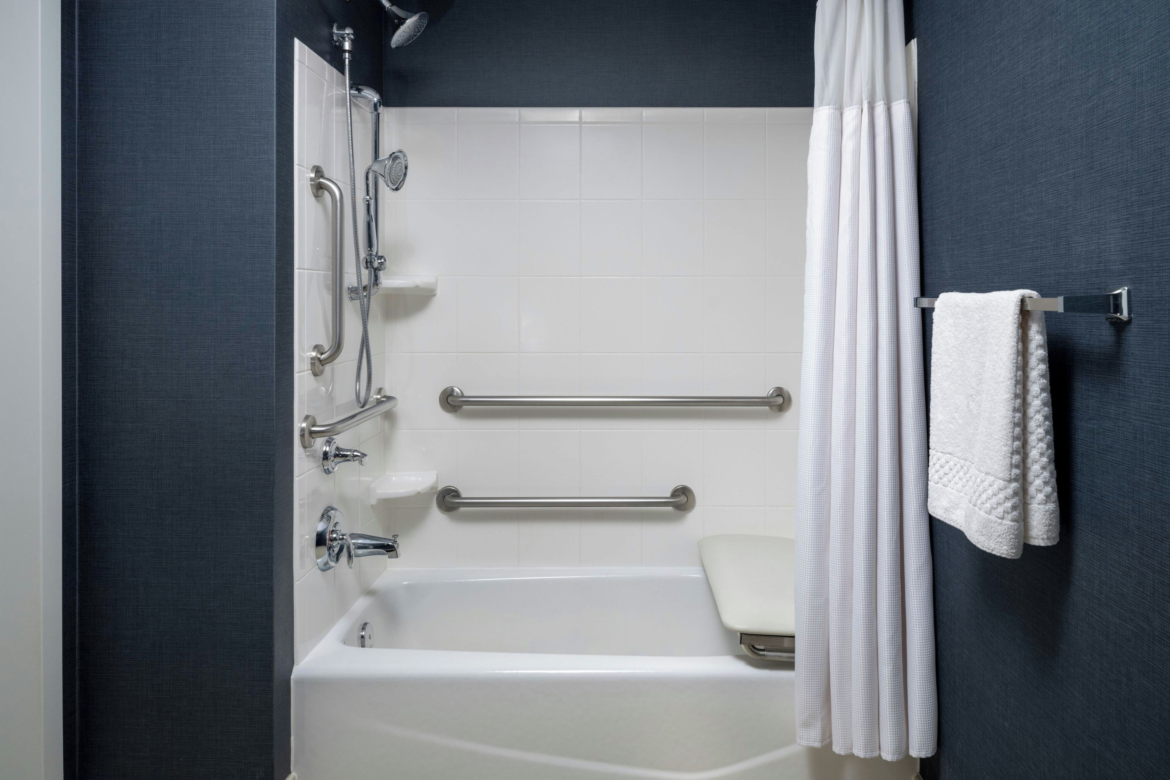 Un baño moderno con bañera, ducha y barras de apoyo.