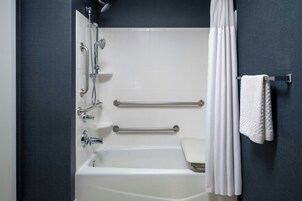 Un baño moderno con bañera, ducha y barras de apoyo.