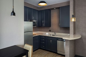 Una cocina moderna con armarios oscuros, electrodomésticos de acero inoxidable y encimera de granito.