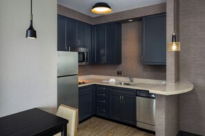 Una cocina moderna con armarios oscuros, electrodomésticos de acero inoxidable y encimera de granito.