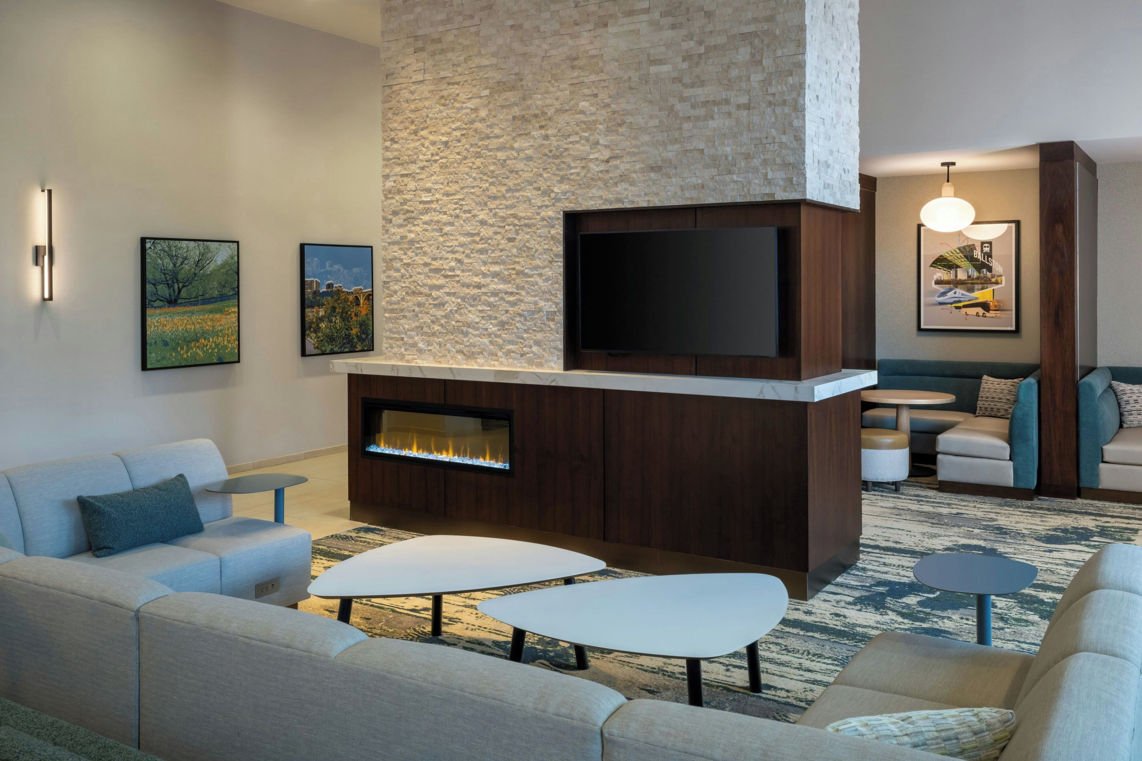 A modern living room with a fireplace, comfortable seating, and artwork on the walls.