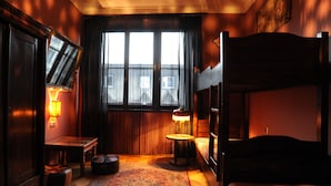 Una habitación con una cama, un escritorio, una lámpara y un ventanal con cortinas.