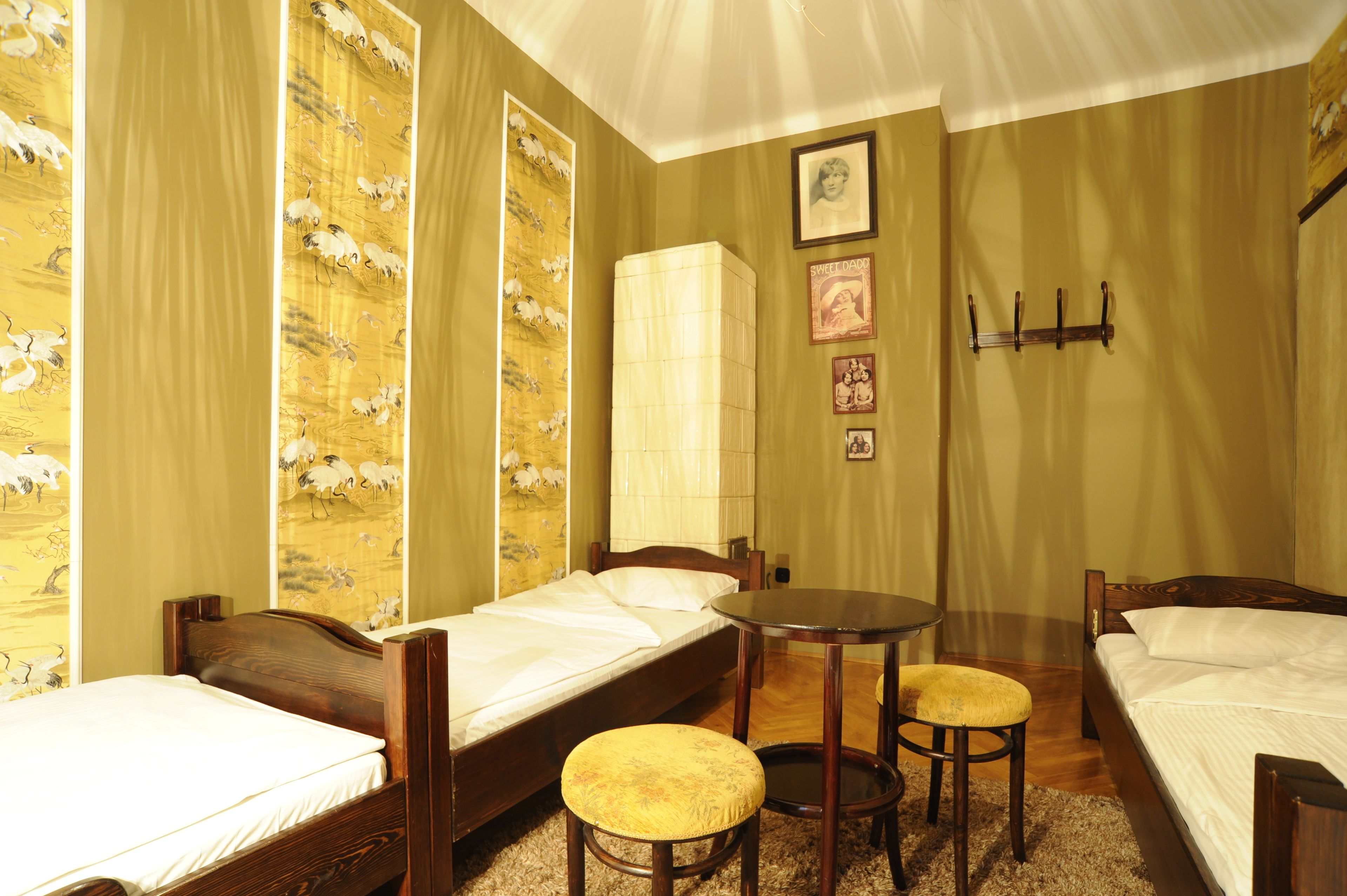 A room with two single beds, a small round table, and a stool.