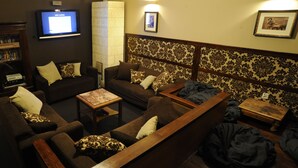 Una sala de estar con sofás, una mesa de centro, un televisor y un papel tapiz estampado.