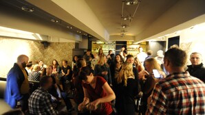Un espacio interior concurrido donde hay gente reunida alrededor de mesas, posiblemente un bar o área social.