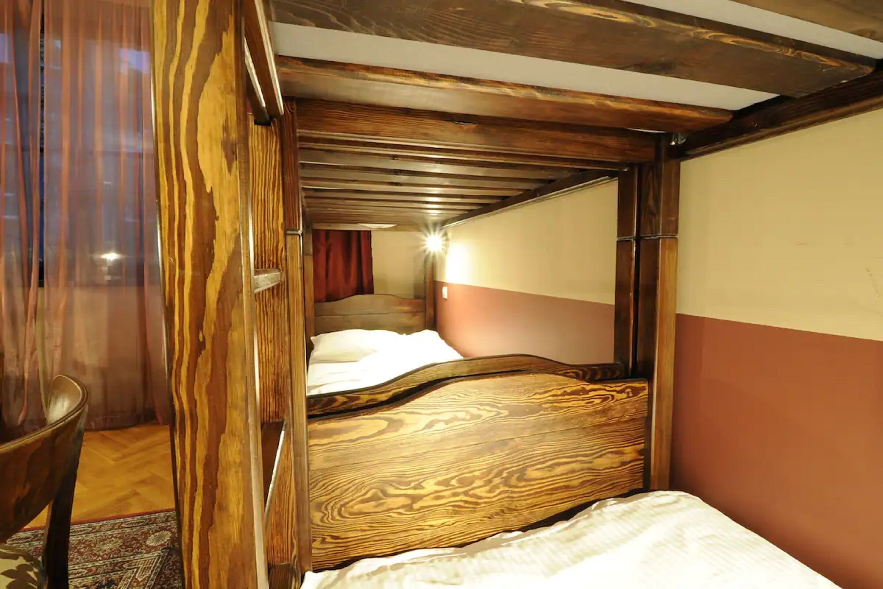 A room with a wooden bed frame, a mirror, and a red curtain.