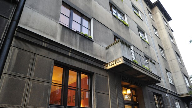 Un edificio con un letrero que dice "HOSTEL DECO". Tiene varias ventanas, algunas con plantas en los alféizares.