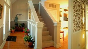 Una escalera con barandillas blancas y un pasamanos de madera, que conduce a una plataforma con una puerta y una ventana.