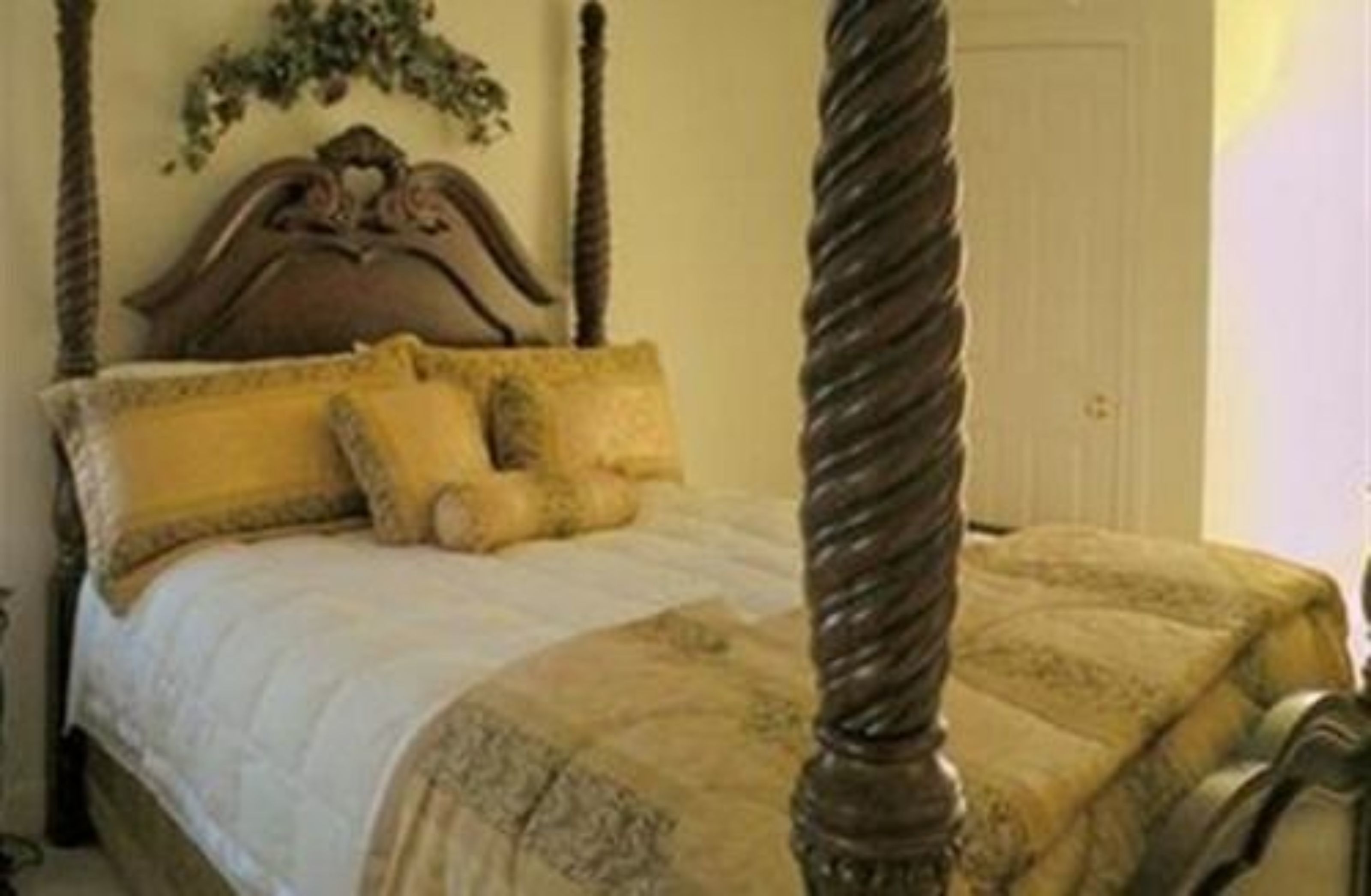 A four-poster bed with a wooden headboard and yellow bedding.