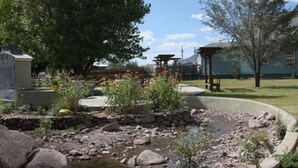Un jardín con un estanque pequeño, rocas y plantas en macetas.