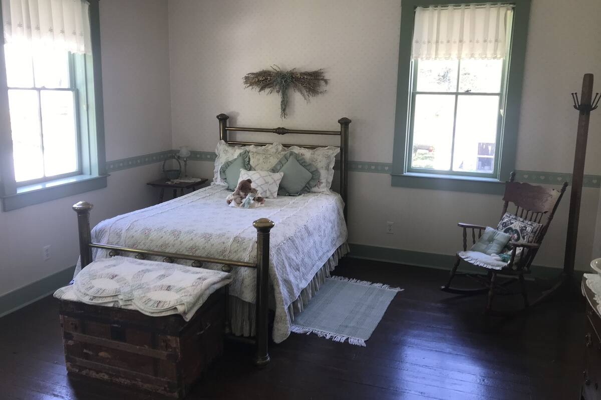 A bedroom with a wooden bed, a rocking chair, and a dresser.
