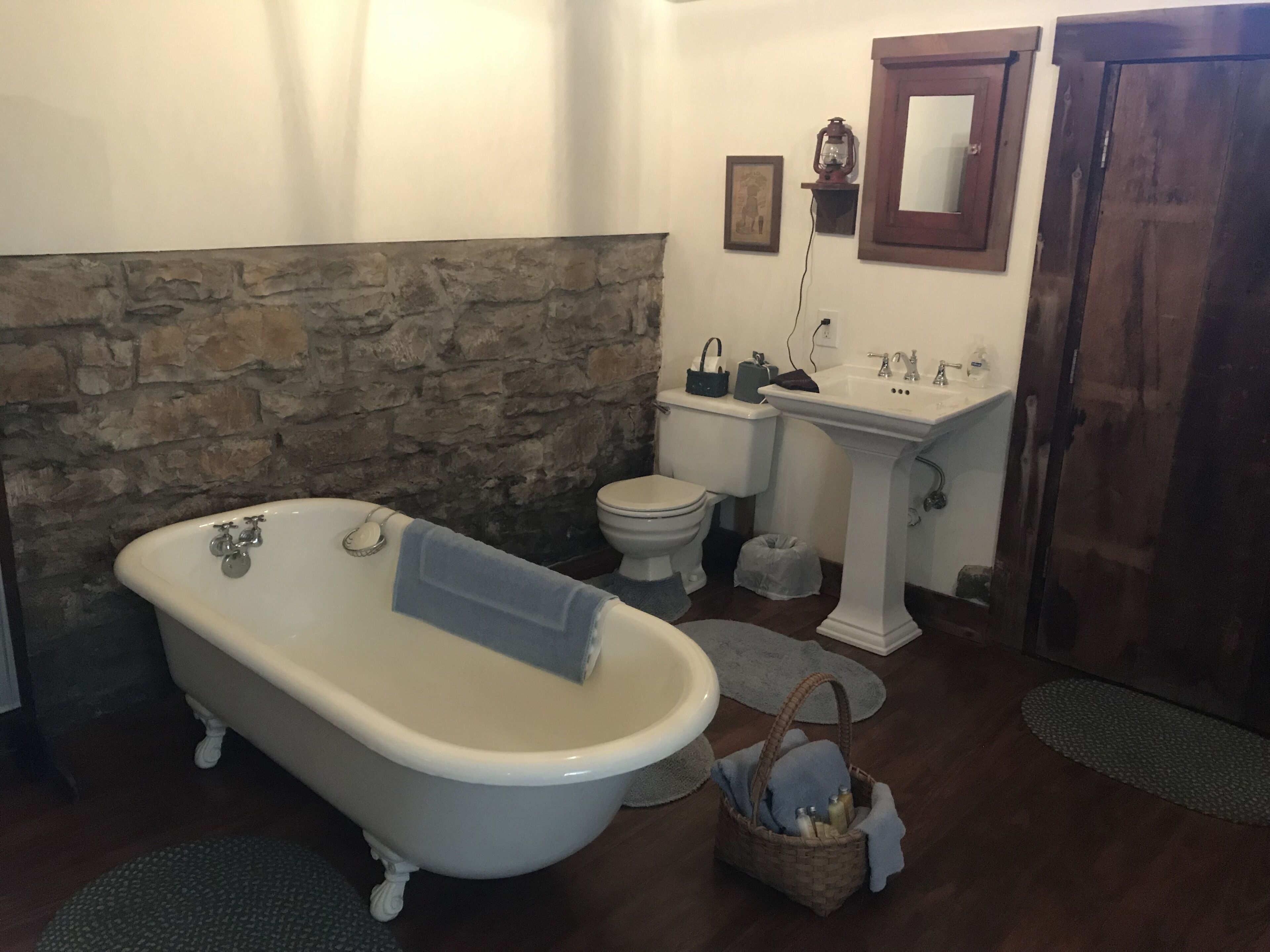 A bathroom with a clawfoot bathtub, a toilet, a sink, and a mirror.