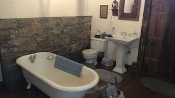A bathroom with a clawfoot bathtub, a toilet, a sink, and a mirror.