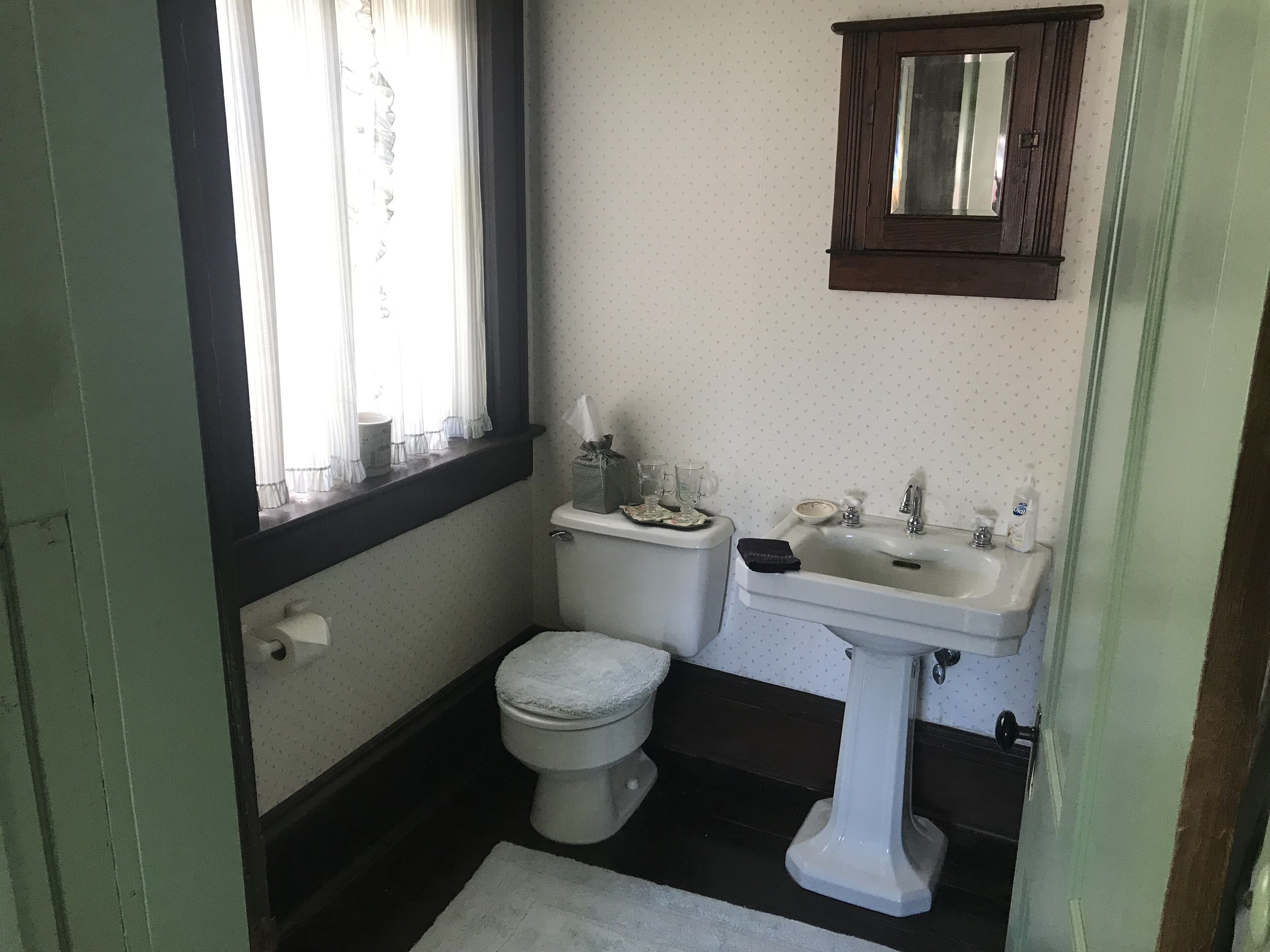 A small bathroom with a toilet, sink, and window.