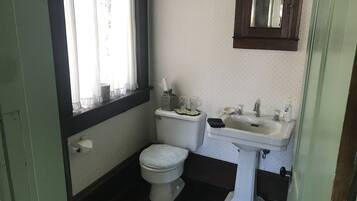 A small bathroom with a toilet, sink, and window.