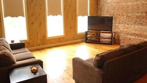 A living room with a brick wall, wooden paneling, and a large window.