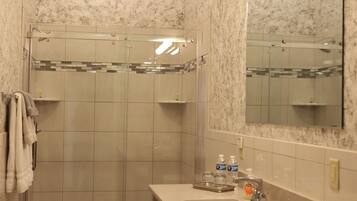 A bathroom with a shower, toilet, sink, and mirror.