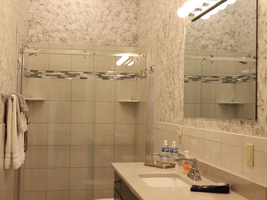 A bathroom with a shower, toilet, sink, and mirror.