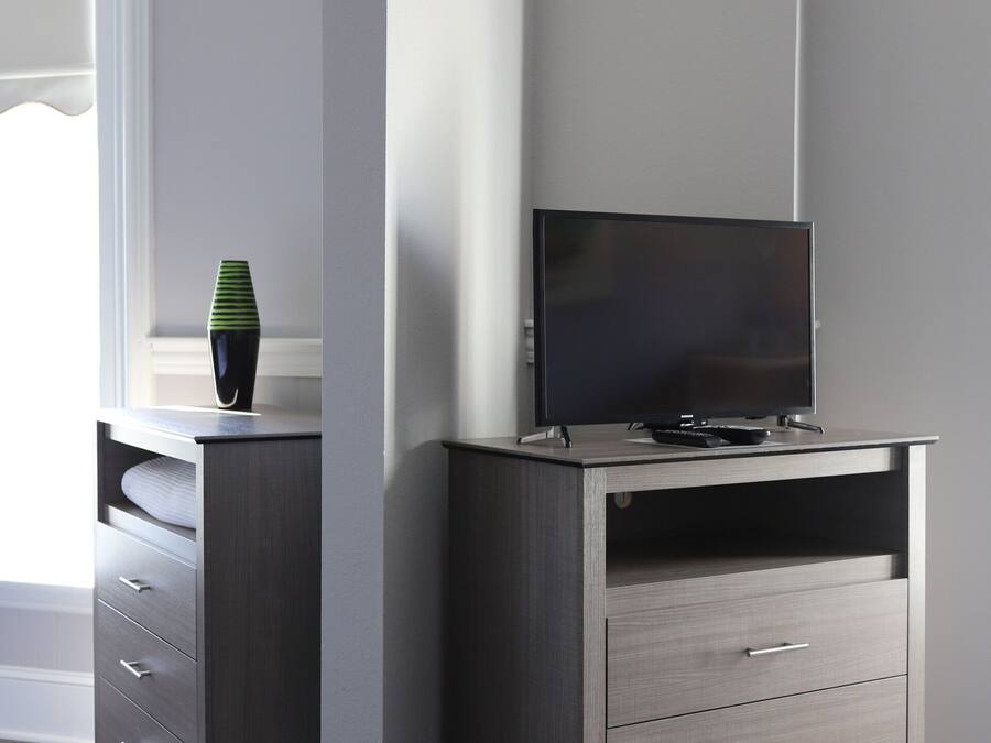 Een moderne woonkamer met een tv-meubel van donker hout, een flatscreen televisie en een vaas op de plank.