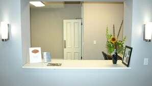 A reception area with a white reception desk, a framed picture, and a vase with flowers.