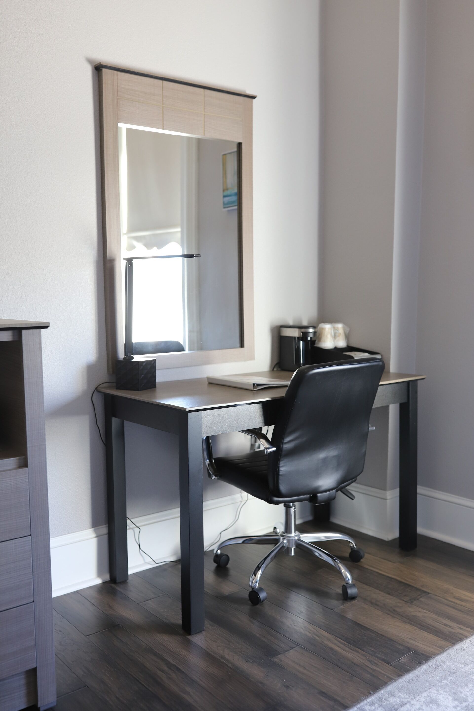 A modern office space with a desk, chair, and a large mirror.