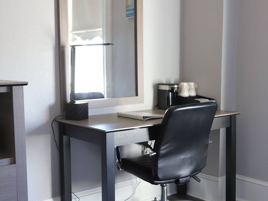A modern office space with a desk, chair, and a large mirror.