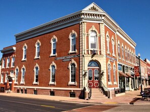 A historic red brick building with a corner entrance, featuring a sign for Denhart Baking Co. and a visible staircase leading to the entrance.