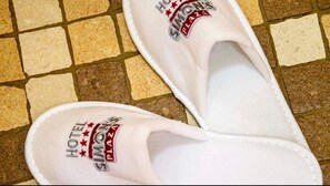 A pair of white slippers with 'HOTEL SIMON'S' printed on them. - Hotel Simon's Plaza (Grevenmacher)
