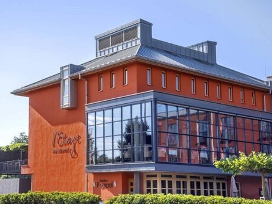 A modern building with a glass facade, a red exterior, and a sign that reads "Hotel".