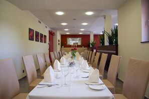 A dining area with a long table set for a formal meal, surrounded by chairs. - Hotel Simon's Plaza (Grevenmacher)