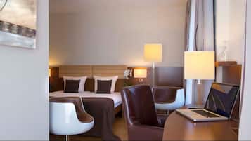 Habitación de hotel con cama, dos sillas, un escritorio y una lámpara.