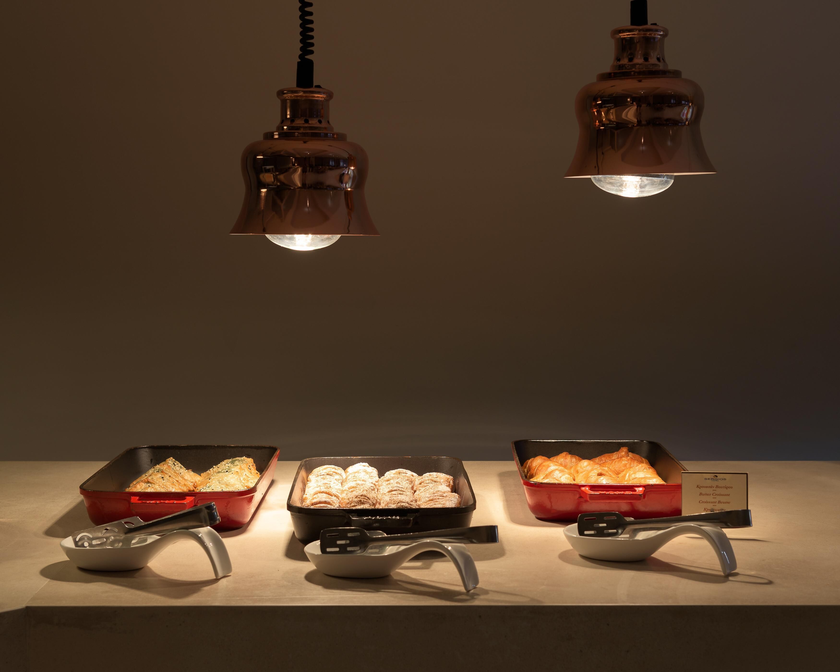 Three red baking dishes with pastries, a white bowl, and a spatula on a countertop.