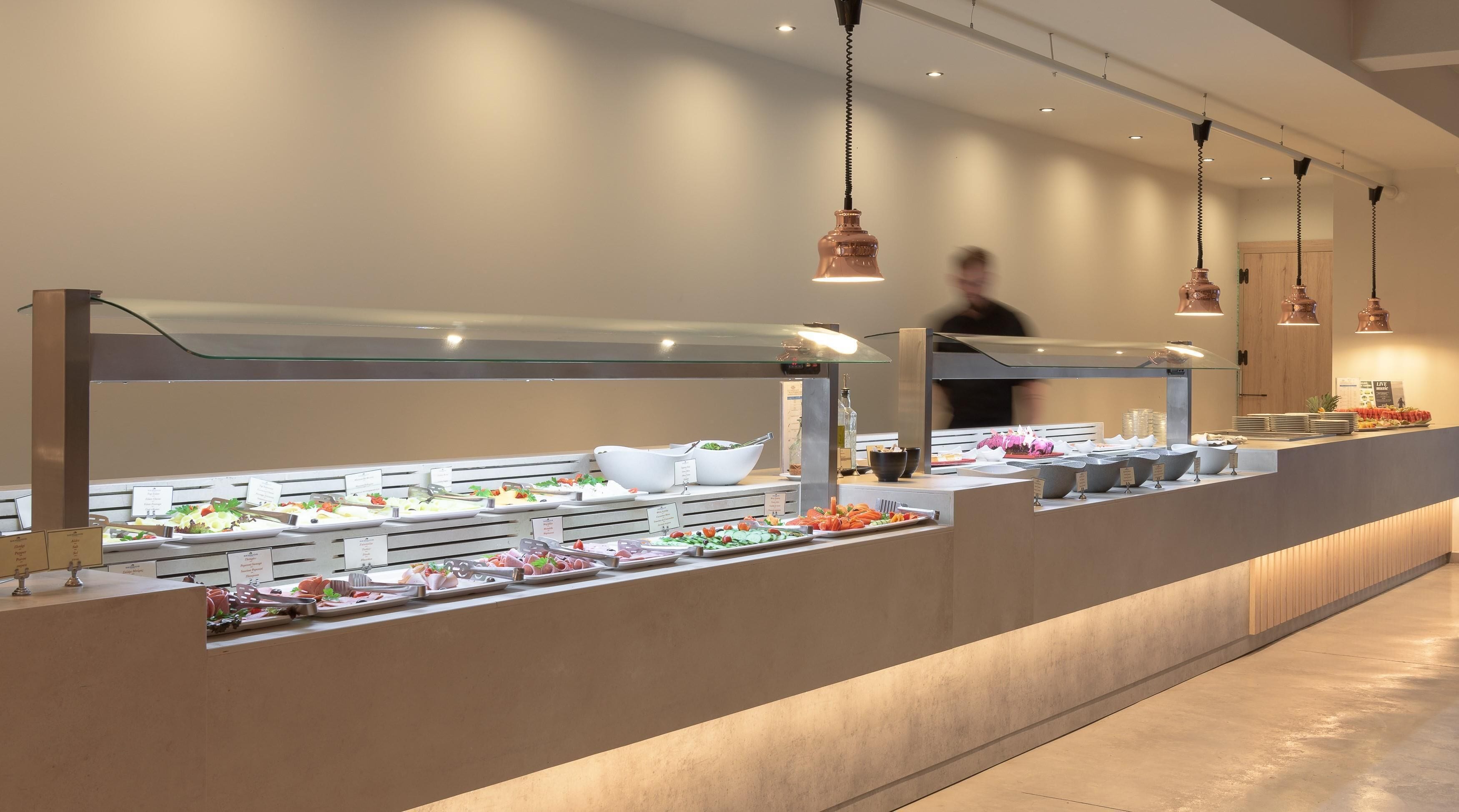 A buffet setup with various food items and a person in the background.